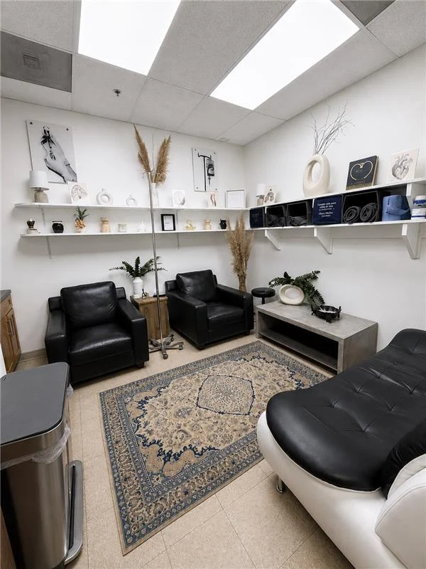 Private IV treatment room at Clínica Médica Guerrero with leather armchairs, an IV stand, decorative shelving and a patterned rug